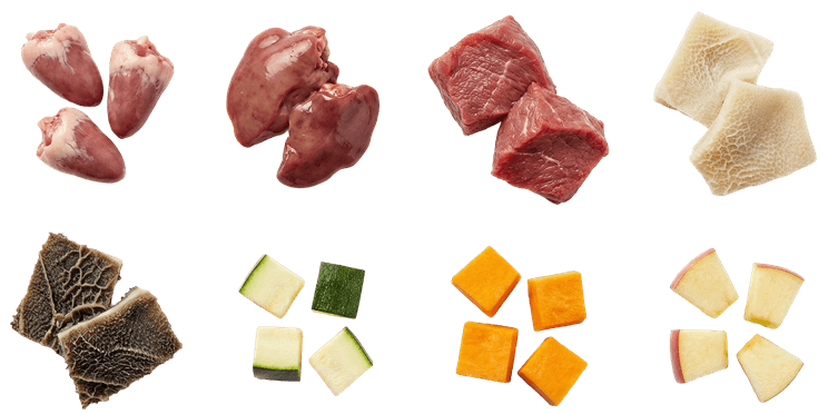 Nyers kutyaeledel összetevők felülnézetből: csirkeszív, csirkemáj, marhahús, pacal, kockázott cukkini, alma és sült sütőtök.